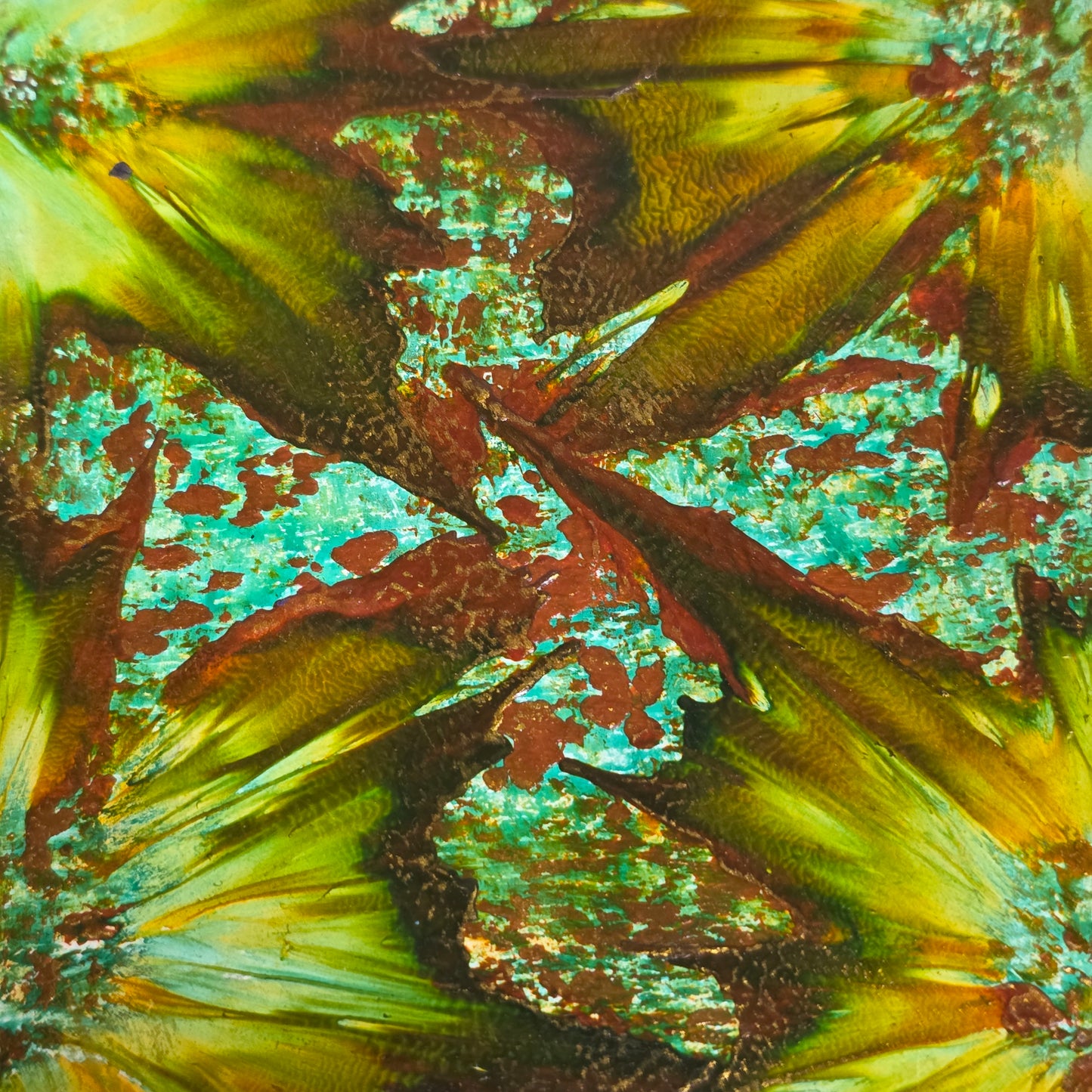 Close-up of a textured encaustic artwork with floral patterns in green, brown, and yellow.