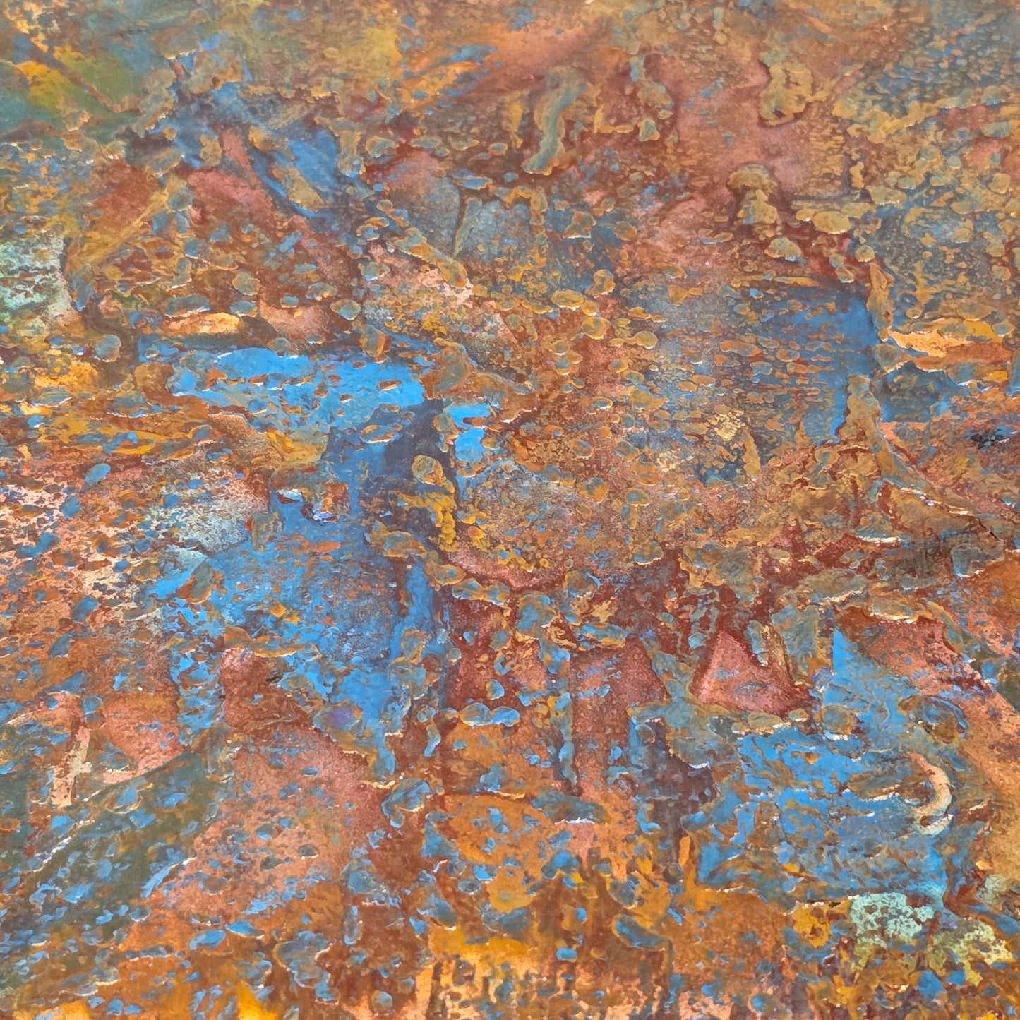 Close-up of rusted metal surface with brown, blue, and orange colors.