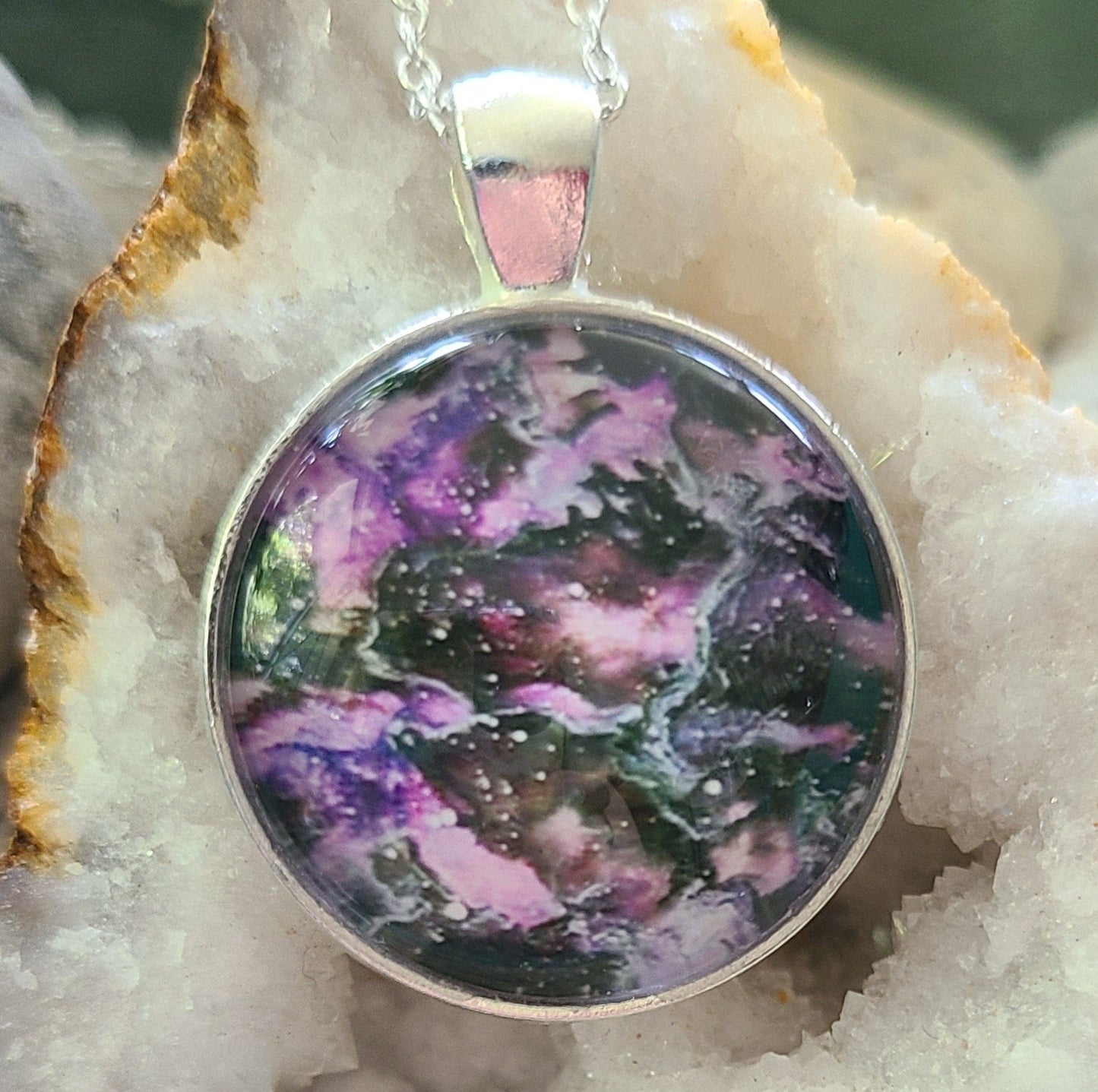 Alisa Marie original artwork, Purple Storm pendant featuring deep purple and black swirled design, set in silver frame with silver chain, displayed on white crystal geode.